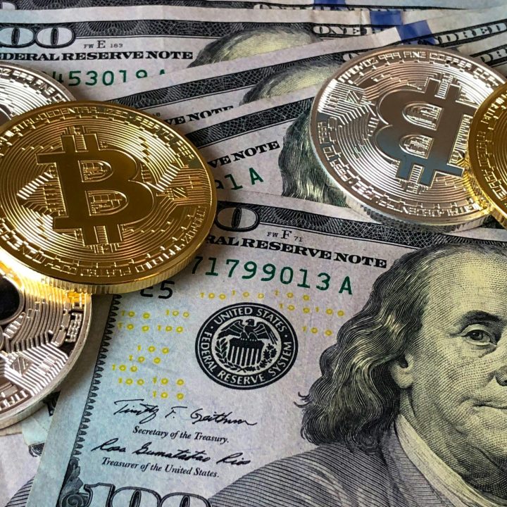 A close-up photo depicting Bitcoin coins on top of US dollar bills, symbolizing finance and cryptocurrency.